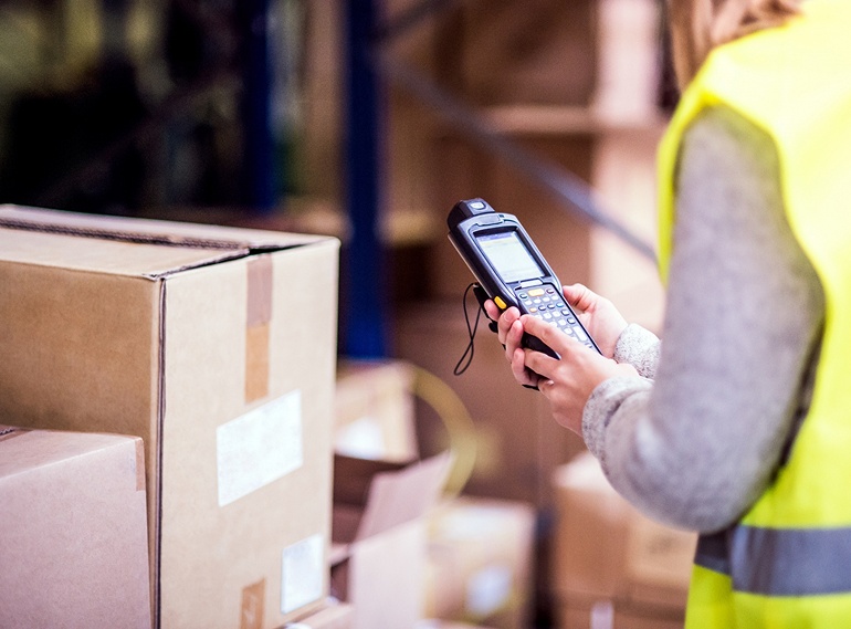 Mitarbeiterin im Lager mit Handscanner erfasst Pakete