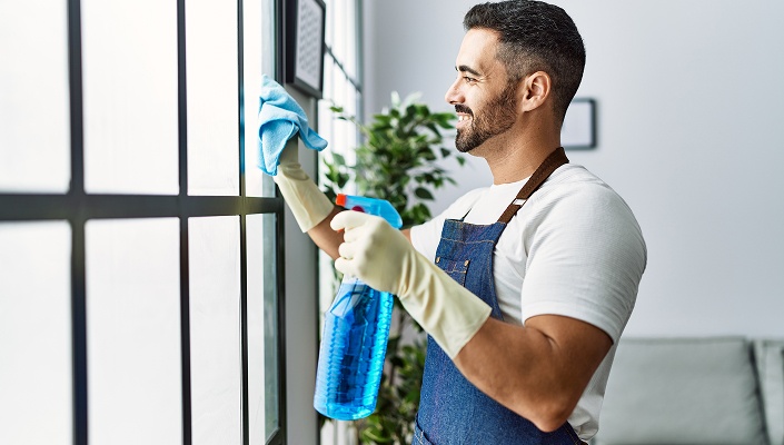 Person säubert Fenster mit Putzbedarf