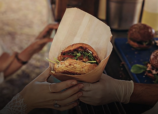 Person überreicht anderer Person einen Burger