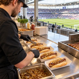 Gastronom im Stadion überreicht Bratwurst zum Mitnehmen